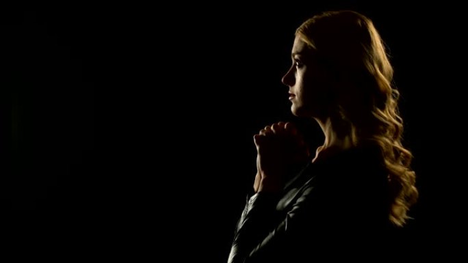 金发女人在黑暗的地方祈祷，请求宽恕，罪人忏悔