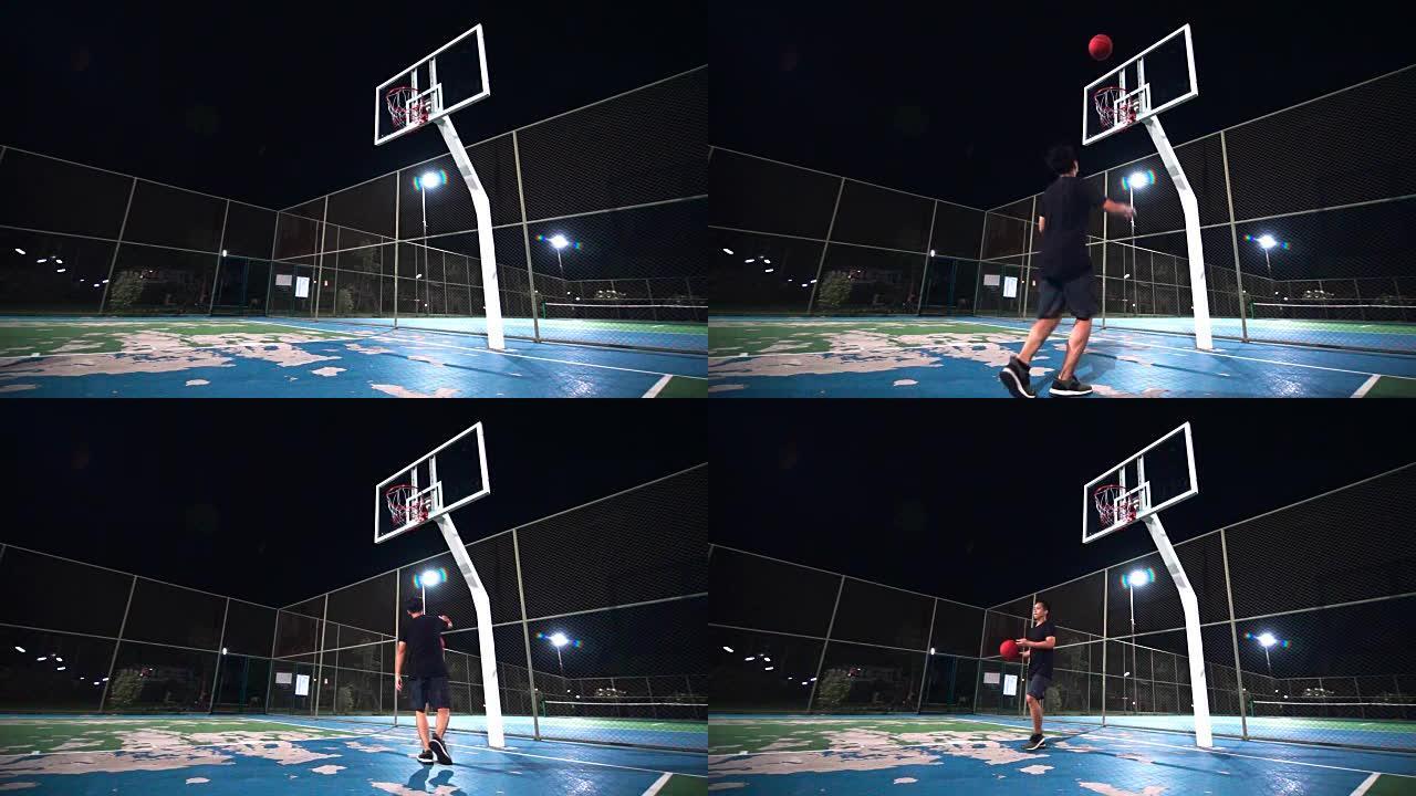 SLO MO体育概念: 一个晚上独自在室外球场上打篮球的人。