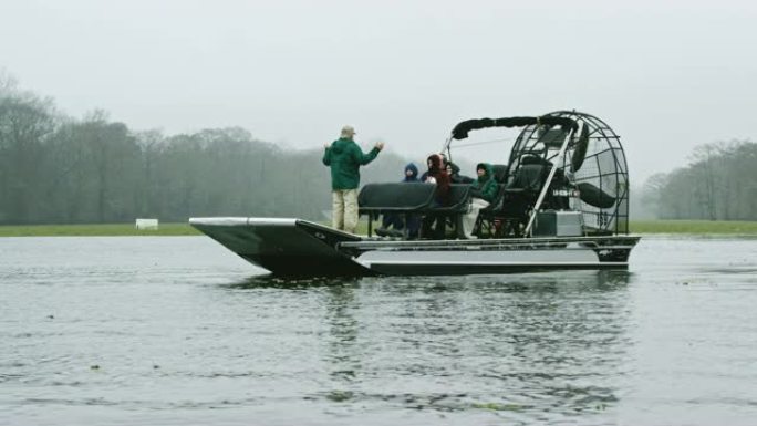在阴暗的天空下，一名导游在路易斯安那州南部Atchafalaya河流域沼泽的一艘汽艇上与游客交谈