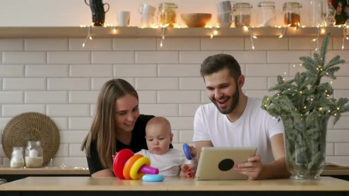 母亲，父亲和婴儿的家庭坐在平板电脑上