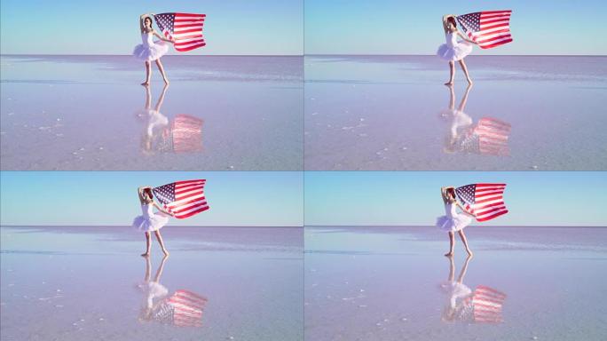 美丽的芭蕾舞演员在水上举着美国国旗。有风的一天。慢动作