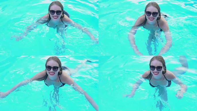 戴着时尚太阳镜的漂亮女士喜欢在清澈的游泳池水中游泳