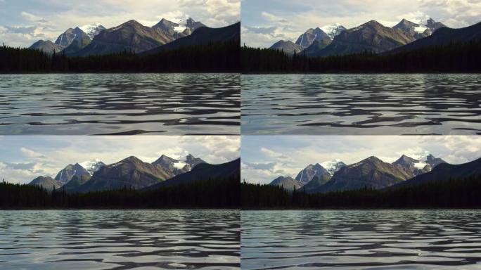加拿大艾伯塔省贾斯珀国家公园的背景中，山湖与森林和加拿大落基山脉轻柔地涟漪