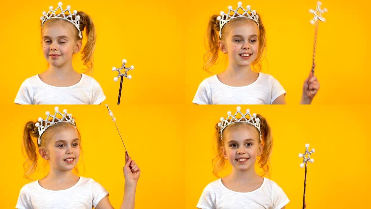 可爱的金发孩子挥舞着魔杖，在镜头前微笑，梦想和童年