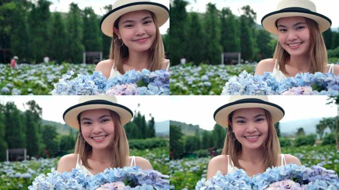 泰国美女，她拿着绣球花花束对着镜头微笑，游客她去了绣球花场。新鲜空气，她很开心