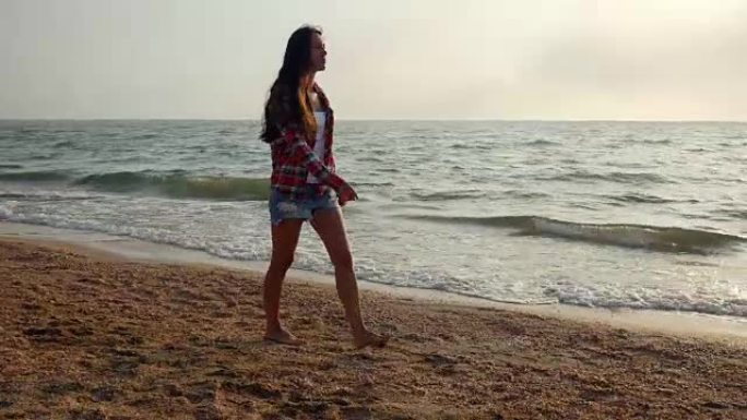 年轻浪漫的女人漫步在海滩上享受日落，跟踪拍摄