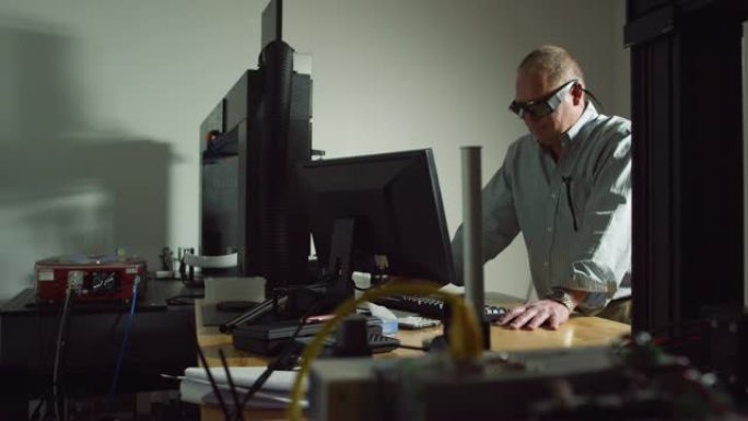 四十多岁的高加索工程师戴着护眼装置在室内制造设施中的计算机上工作