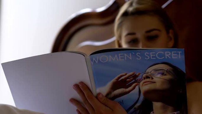 年轻女性在床上阅读女性杂志，在家放松，周末休息