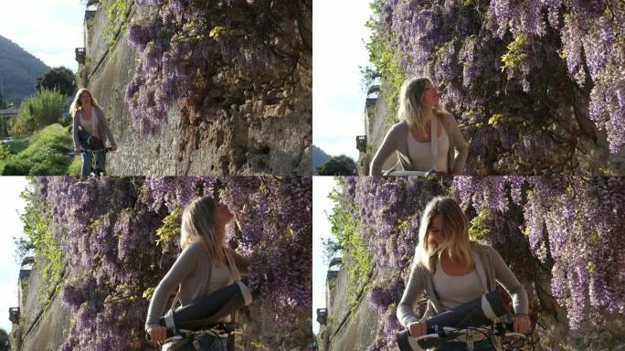 年轻的女自行车手在日出时经过紫藤花