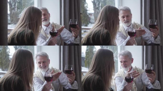 高级高加索男性侍酒师与年轻女子谈论葡萄酒的味道和笑声。快乐成熟的退休人员和快乐的黑发女孩在室内休息。