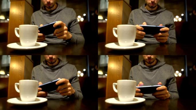 年轻人坐在咖啡馆里，在智能手机上玩电子游戏，小工具成瘾