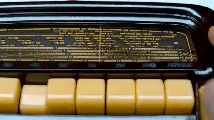 一个男人正在一个古老的古董收音机上寻找一个音乐电台