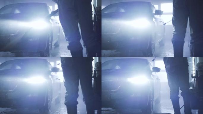 无法识别的男性工人使用高压喷雾器用清洁水清洗车辆。汽车护理店，服务站，维修。