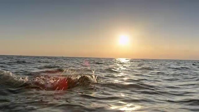 TS男游泳者在日落时在波涛汹涌的大海中游泳前爬行