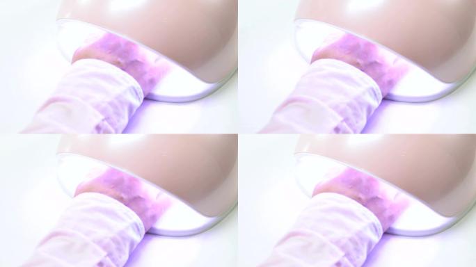 女性客户在紫外线灯下用凝胶抛光剂固化指甲，用于聚合