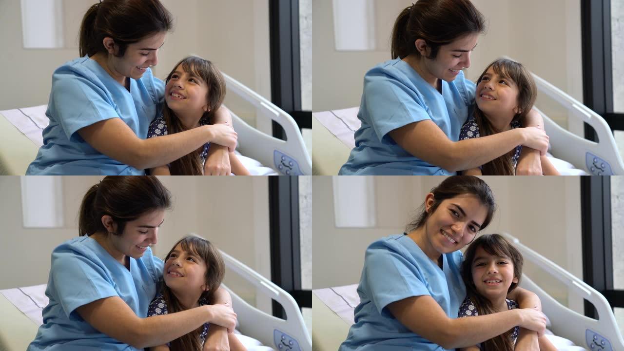 爱心护士拥抱住院的小病人，互相看着对方，然后面对镜头微笑