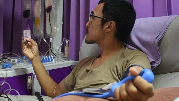 这名年轻人在医院读献血卡，并在单次献血者血小板血液时挤压手中的球。
