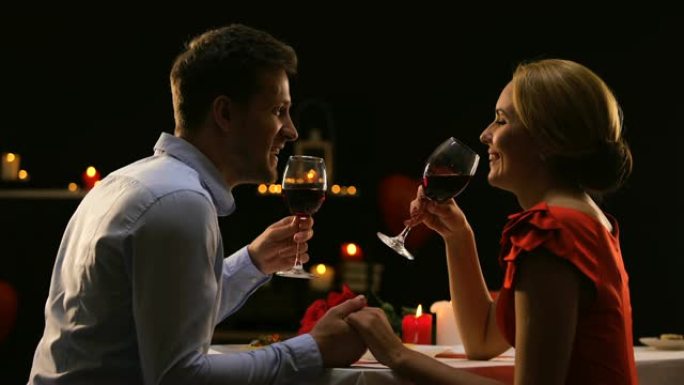 甜蜜的夫妇用红酒碰杯，在高品质的餐厅约会