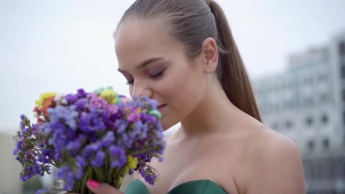一个穿着别致连衣裙的可爱女孩的肖像，闻到一束芬芳的野花。
