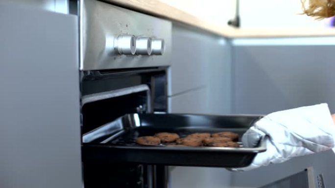 女人从烤箱里拿巧克力饼干，自制烘焙食谱，甜点