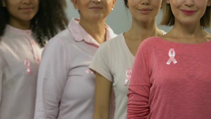 一群带着粉红丝带的健康女性对着镜头微笑，进行抗癌运动
