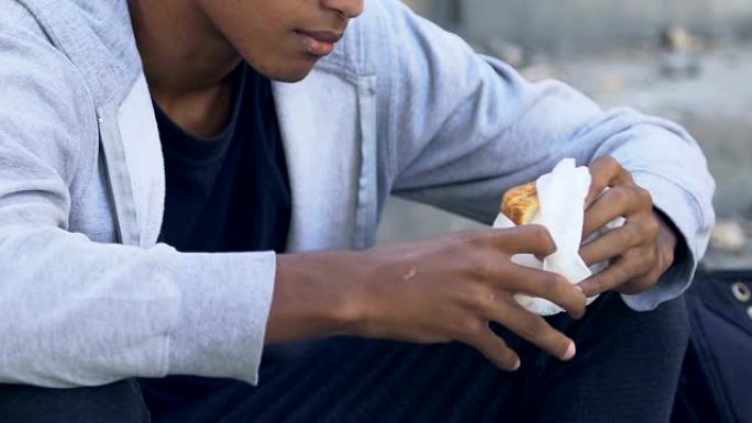 悲惨的非洲裔美国年轻男性独自在户外吃三明治，问题