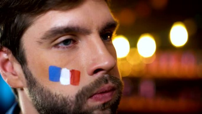 焦急的法国球迷与彩旗在脸颊使捂脸，失望