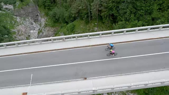 在两个公路自行车手越过峡谷上方的桥梁上方的空中