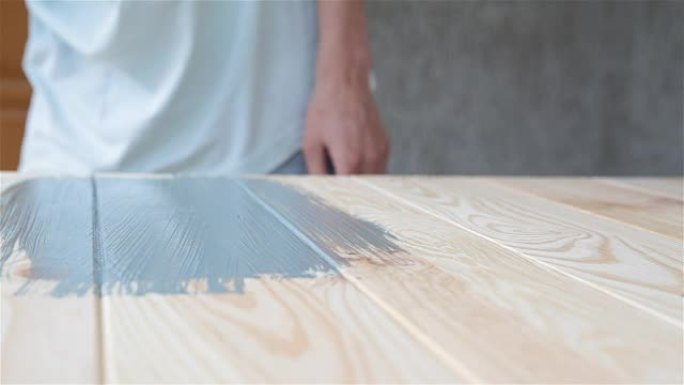 木匠用蓝色油漆覆盖木质表面。