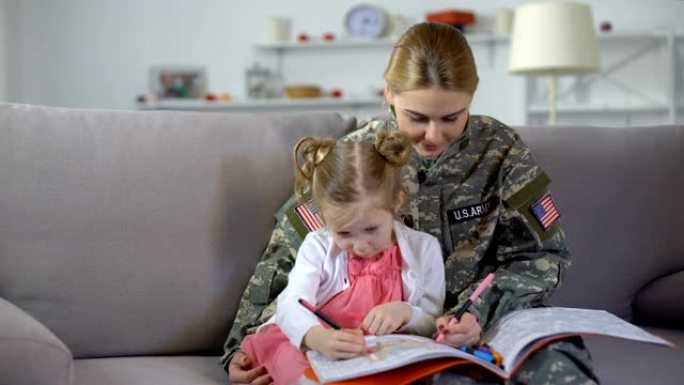 可爱的小女孩和美国兵妈妈在家里的涂色书里画画，放松心情