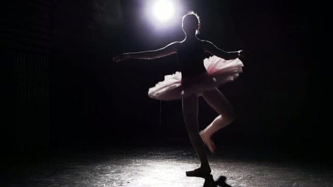 美丽的年轻优雅芭蕾舞演员在黑色混凝土地板背景的足尖鞋上。芭蕾舞练习。慢动作。