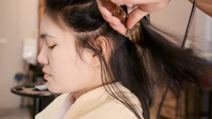 亚洲美女她在沙龙里使用洗发和吹发服务。