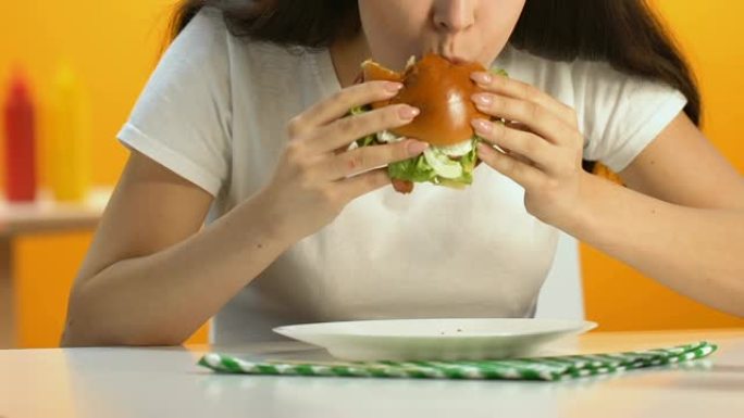 女性在快餐店吃食欲旺盛的脂肪汉堡，饮食，肥胖