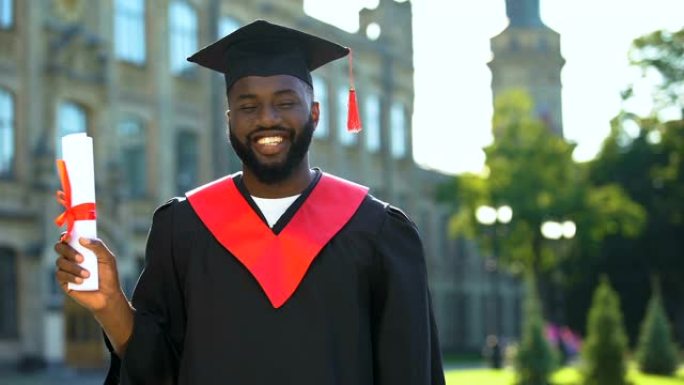 激动的非洲裔美国学生穿着毕业礼服，拿着文凭相机
