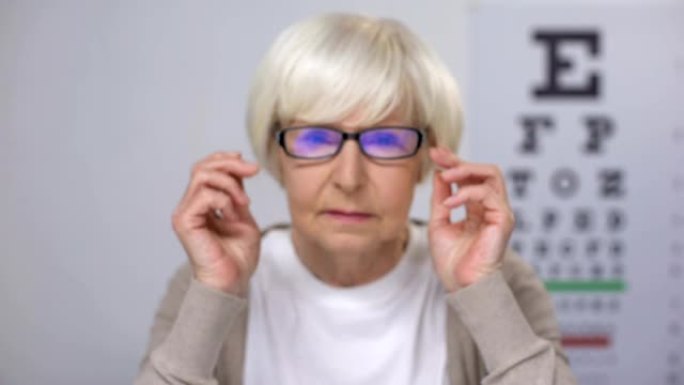 老年女士将眼镜放在广告上，试图集中视觉，对结果不满意