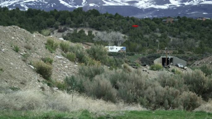 三十多岁的高加索人使用正手驱动器在圆盘高尔夫球场 (飞盘高尔夫) 的草地，多山的风景中长距离投掷圆盘