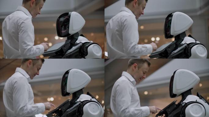 一名男子与机器人机器人站在一起，向他提问，并通过点击机器人身体上的屏幕寻求帮助。