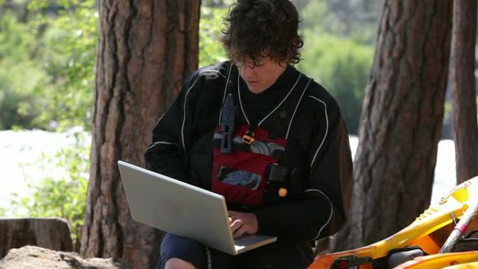 皮划艇运动员在户外使用笔记本电脑坐下
