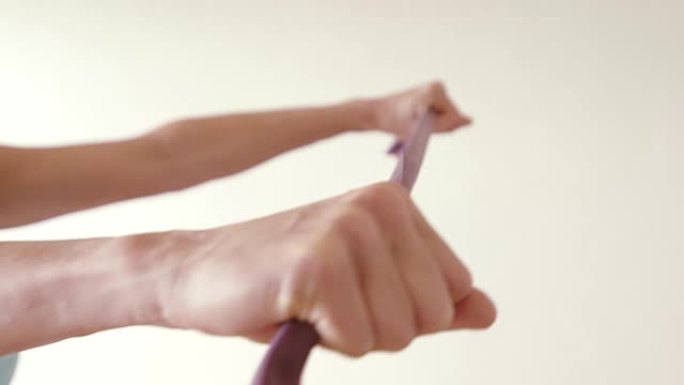 一个成熟的女人在她的家庭健身房使用弹力带。