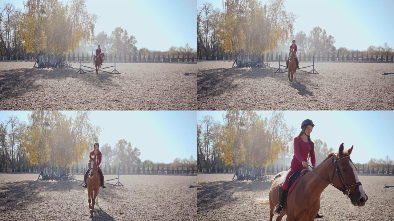 穿着粉红色衣服和骑马头盔的年轻高加索女孩跳过优雅的棕色马的障碍，并从射击中骑行。室外畜栏专业女子马术