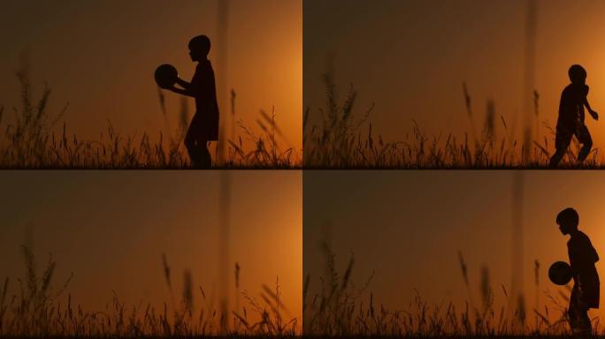 剪影日落时一个男孩在田野里玩杂耍。