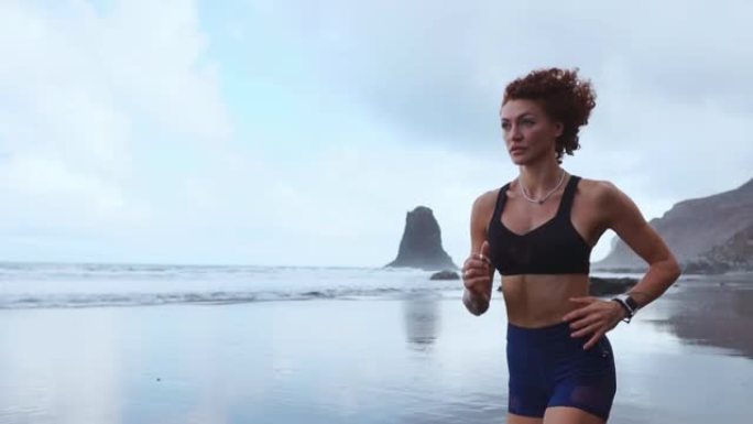 穿着运动服的漂亮女孩运动员早上沿着大西洋海岸奔跑。健康生活方式的概念。运动体质