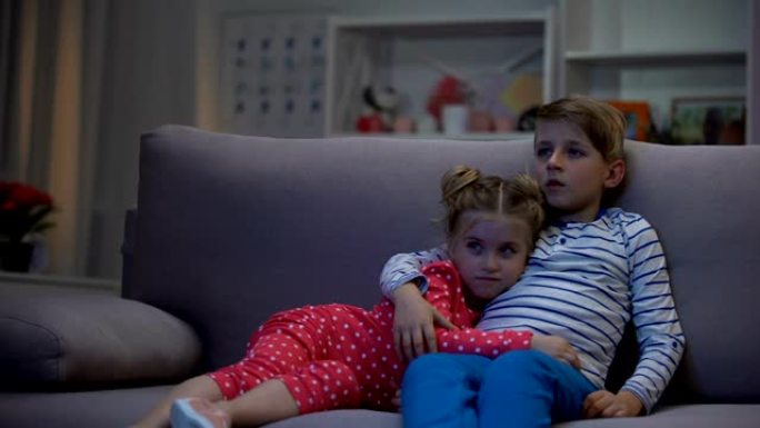 可爱的兄妹拥抱沙发看电影，小玩意休闲，电视