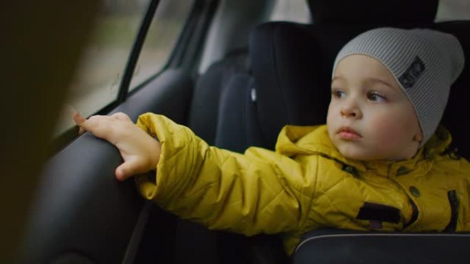 男孩看着车窗。和家人一起旅行。男婴看着窗外的汽车驾驶公路旅行。可爱的蹒跚学步的男孩坐在行驶中的汽车座