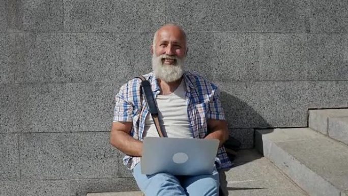 带笔记本电脑的大胡子老人欢迎某人