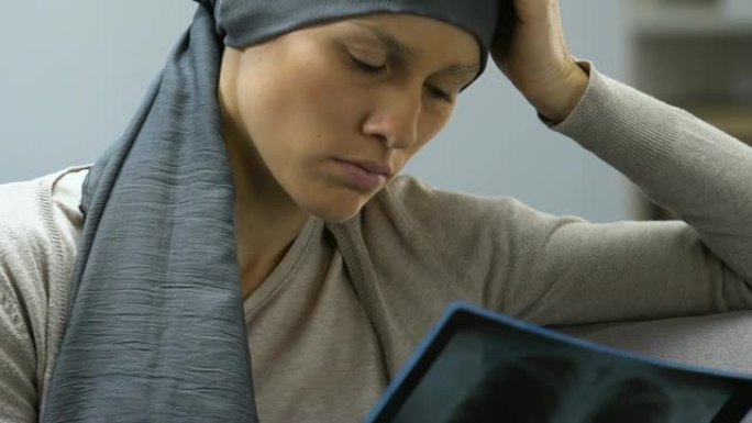 患有癌症的悲伤女人看着x射线图像，灰心丧气，没有挣扎的意愿