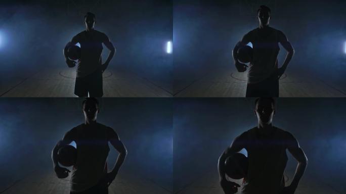 篮球运动员走到摄像机前，将球敲在地上，然后停下来拿着球看着摄像机