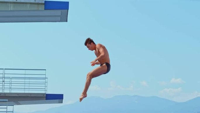SLO MO男性高潜水员脱下木板，在空中旋转并跳入游泳池