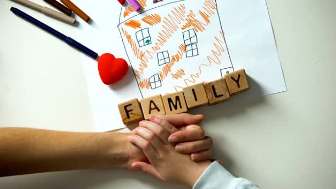 儿童牵着成年人的手，家庭词由房子图片上的立方体制成