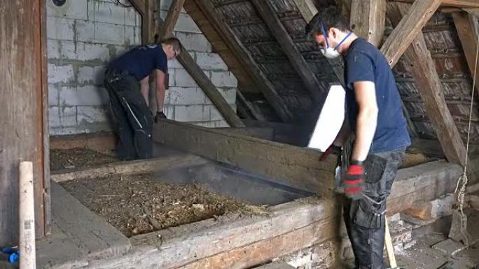 两名工人在阁楼上拆除地板